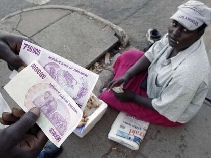 Un cambista muestra un billete de 50 millones de dólares zimbabuenses en un mercado informal de cambio de Harare.