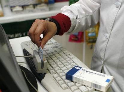 Una farmac&eacute;utica pasa una tarjeta del sergas para leer los datos 