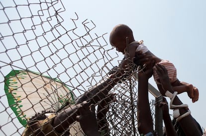 Un bebé es pasado a través de una valla que rodea un punto de distribución de ayuda, en el interior del campamento de desplazados en el Aeropuerto Mpoko en Bangui, República Centroafricana.