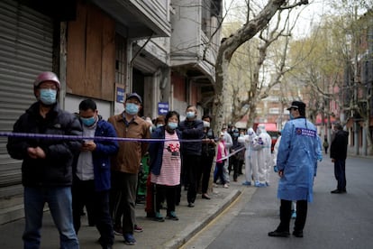 Una fila de vecinos Shanghái que esperaban el miércoles para comprar comida en una zona acordonada y controlada por la policía.