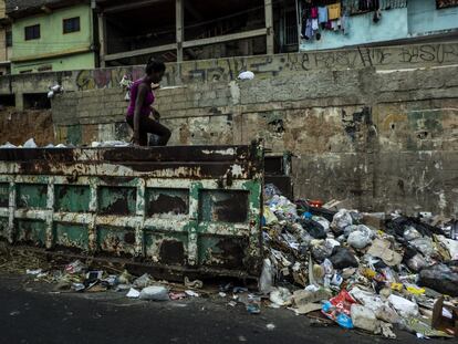 Moradores do o bairro de Petare procuram comida em um contêiner de lixo, em março de 2019 em Caracas, Venezuela.