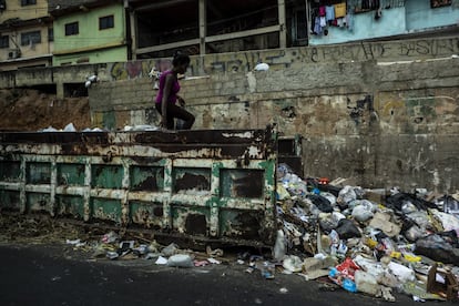 Moradores do o bairro de Petare procuram comida em um contêiner de lixo, em março de 2019 em Caracas, Venezuela.