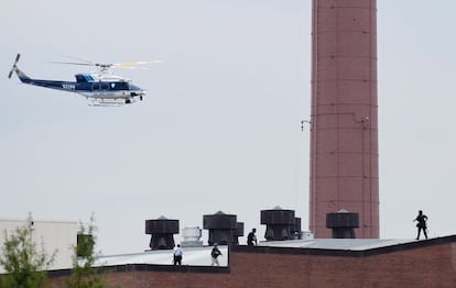 Un helicóptero de la policía sobrevuela el edificio del mando de la Armada en Washington mientras varios policías caminan sobre el tejado del edificio.
