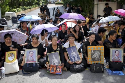 Tailandeses sujetan retratos del rey Bhumibol Adulyadej mientras aguardan a que su cadáver sea trasladado desde el hospital Siriraj, en Bangkok (Tailandia).