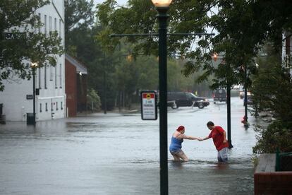 Dos vecinos cruzan una calle inundada de una zona residencial de New Bern (Carolina del Norte), el 13 de septiembre.