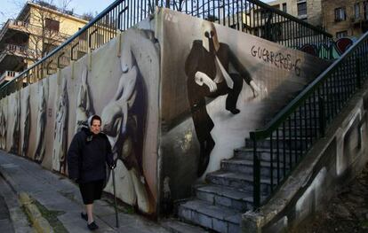 Una mujer, junto una pintada que representa un hombre de negocios con un casco de espartanos, en el centro de Atenas.