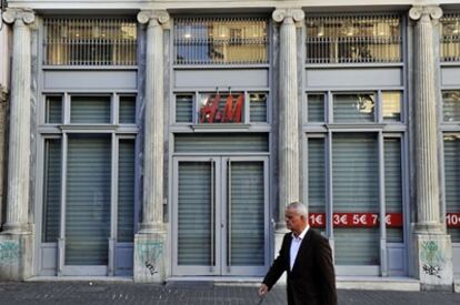 Un hombre camina frente a una tienda cerrada a cal y canto en la primera jornada de la huelga general de 48 horas contra las protestas.