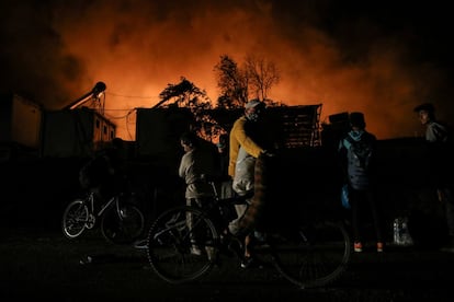 A primera hora de la mañana del miércoles, varias brigadas de bomberos habían controlado el primer fuego pero aún seguía activo en partes del campamento, que ha quedado prácticamente destruido. En la imagen, una pareja de migrantes camina por el interior del campamento durante el incendio.