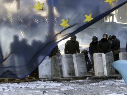 Varios policías antidisturbios tras una bandera de la UE en Kiev. 