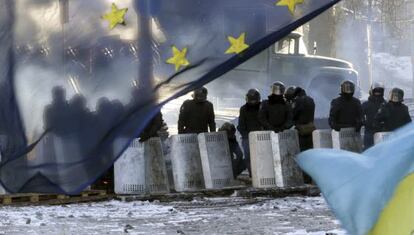 Varios policías antidisturbios tras una bandera de la UE en Kiev. 