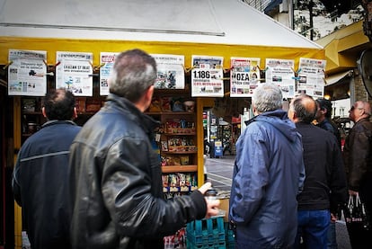 A la derecha, transeúntes leen la prensa en un quiosco, una afición muy común en Atenas, donde es habitual hallar grupos discutiendo de política.