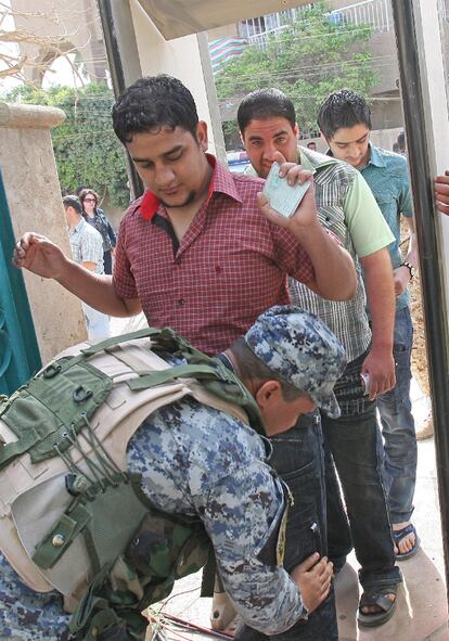 Un agente de seguridad iraquí cachea a un futuro votante. Los atentados han dejado decenas de muertos en la jornada de elecciones.