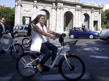 Ana Botella pasea en bicicleta por la Puerta de Alcalá.