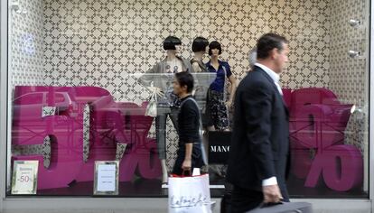 Dos consumidores andan frente a una tienda de moda en Par&iacute;s (Francia).