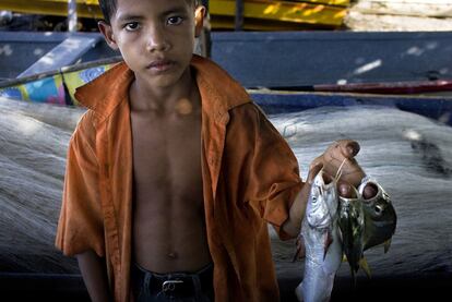 Un niño muestra su paga por ayudar a la descarga del pescado en Potosí.