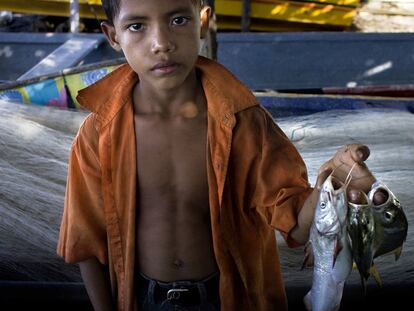 Un niño muestra su paga por ayudar a la descarga del pescado en Potosí.