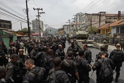 Policías y vecinos rodean un carro blindado desplazado ayer a la favela de Villa Cruzeiro, en Río de Janeiro.