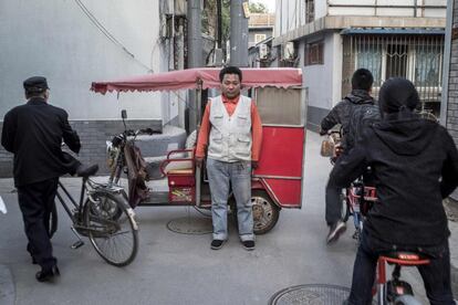 Un conductor posa junto a su bicitaxi en una calle de Pekín.