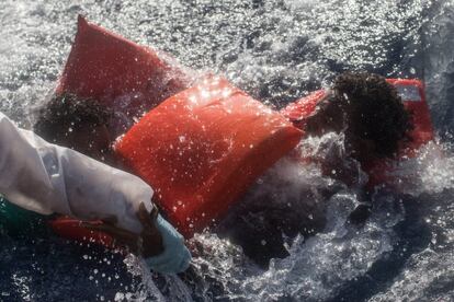 Los miembros de la tripulación del buque 'Phoenix' ayudan a un hombre a entrar en un bote de rescate después de que su embarcación de madera volcase frente a Lampedusa, una isla de Italia.