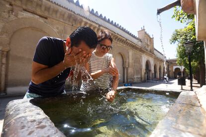 Dos turistas se refrescan este miércoles en una de las fuentes del Patio de los Naranjos de la Mezquita de Córdoba.