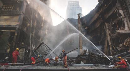 Un equipo de bomberos trabaja para extinguir el incendio prendido por bandas de opositores en el centro comercial Central World, en Bangkok.