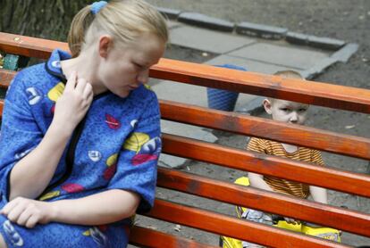 Un niño mira a través de un banco mientras juega cerca de su madre en la ciudad de Korostyshiv (Ucrania), el 30 de julio de 2015.