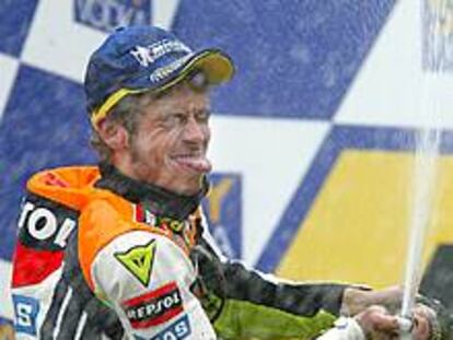 Valentino Rossi, con la lengua fuera y una botella de cava, festeja su triunfo en el podio.