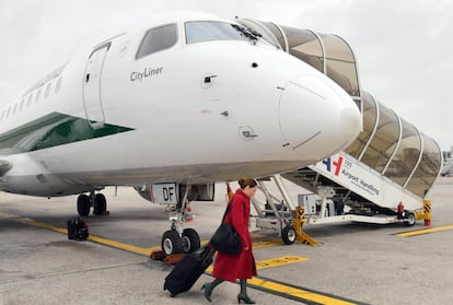 Una azafata embarca un avi&oacute;n de la aerol&iacute;nea italiana Alitalia en el aeropuerto de Mil&aacute;n.