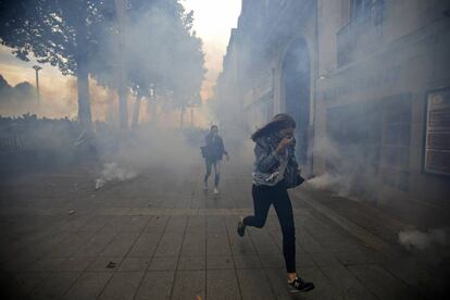 Manifestantes intentan ponerse a salvo del gas lacrimógeno durante una protesta en contra de la nueva ley del trabajo francesa, en París.