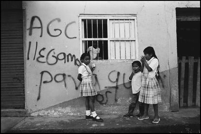 Niños de pie junto a un grafiti en una pared, traducido como: "AGC (Autodefensas de Colombia) hemos venido para quedarnos". Policarpa, Colombia, julio de 2009.