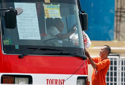 El negociador filipino entrega al conductor del autobús comida para los rehenes. En la luna del autobús, las condiciones del secuestrador.