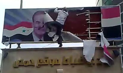 Un hombre destroza un cartel con la imagen del presidente El Asad en la ciudad deHoms, al norte de Damasco.