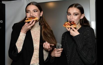 Dos modelos reponen fuerzas en un descanso de un duro día de pasarelas. Con qué. Con lo más socorrido: la pizza.