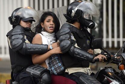 Dos policías venezolanos conducen detenida a una mujer, a la que llevan en una moto en Caracas. 28 personas fueron detenidas aquel día de marzo en el que hubo protestas contra el Gobierno de Nicolás Maduro.