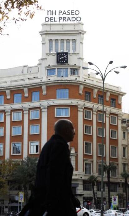 Un viajero pasa frente a la fachada del hotel NH Paseo del Prado.