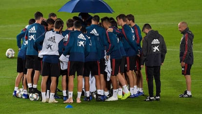 Los jugadores españoles, protegidos de la lluvia con un paraguas en un entrenamiento en el estadio de Gran Canaria.