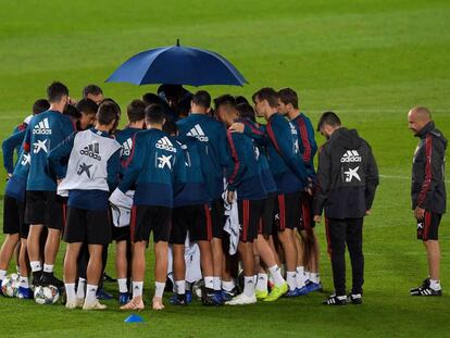 Los jugadores españoles, protegidos de la lluvia con un paraguas en un entrenamiento en el estadio de Gran Canaria.