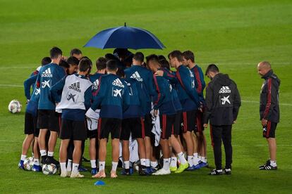 Los jugadores españoles, protegidos de la lluvia con un paraguas en un entrenamiento en el estadio de Gran Canaria.