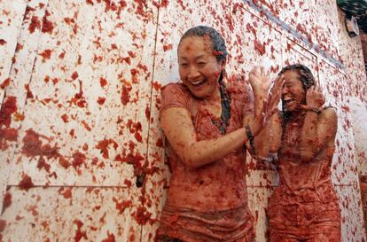 Dos mujeres se cubren ante la lluvia de tomates de La Tomatina.