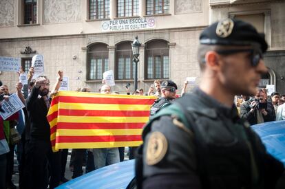 Varios manifestantes sostienen una bandera catalana tras los agentes de la Guardia Civil.  