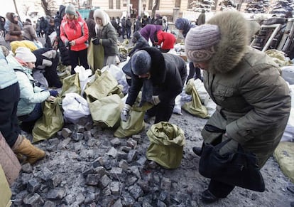 Las mujeres recogen piedras para los manifestantes pro-europeos en el lugar de los enfrentamientos con la policía antidisturbios en Kiev.