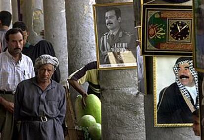 Un hombre mayor pasea en un mercado popular frente a una imagen del presidente iraquí Sadam Husein.