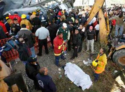 El cuerpo de una de las víctimas yace cubierto por una sábana en el lugar del accidente.