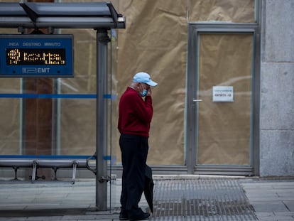 A man waits at a bus stop on Gran Vía avenue in Madrid.