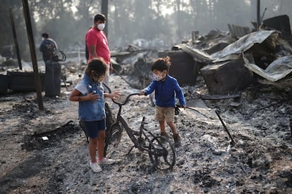 Ashely de 3 años y Ethan de 2, miran en su bicicleta quemada después de que los incendios forestales destruyeran su casa en Oregón.