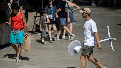 Un joven carga con un ventilador mientras camina por las calles de Barcelona.