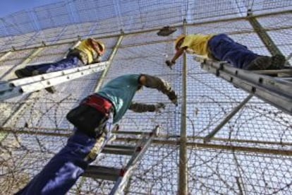 Operarios instalaban ayer viernes alambres con cuchillas en la valla de Melilla.