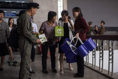 Algunos visitantes norcoreanos salen del lugar con los productos que han adquirido.