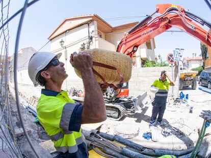 Un operario bebe agua en un descanso mientras realiza tareas de canalización de aguas en una calle de Granada.