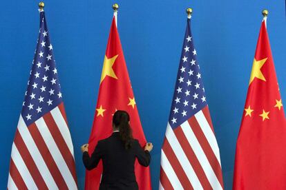 Una mujer china ajusta la bandera nacional junto a las banderas de Estados Unidos antes de la reunión del Diálogo ampliado Estratégico en Pekín.